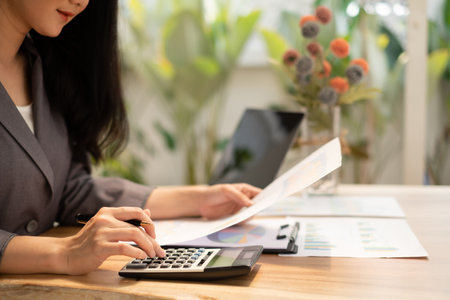 Asian businesswoman sit at their desks and calculate financial graphs showing results about their investments, plan a successful business growth process.の写真素材
