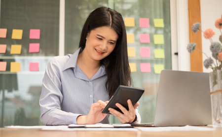 Asian businesswoman sit at their desks and calculate financial graphs showing results about their investments, plan a successful business growth process.の写真素材