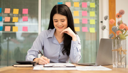 Asian businesswoman sit at their desks and calculate financial graphs showing results about their investments, plan a successful business growth process.の写真素材