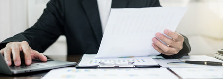 The businessman hand sits at their desks and calculates financial graphs showing the results of...