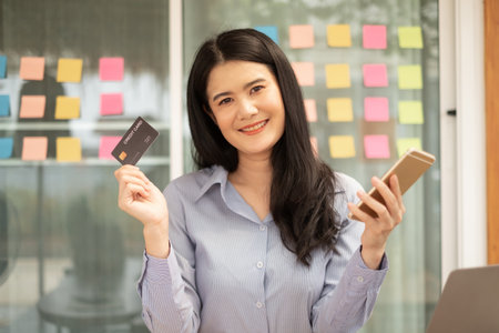 Asian girl shopping online holding credit and using smartphone enter their card number in the mobile phone app to purchase and payment in internet store.の写真素材