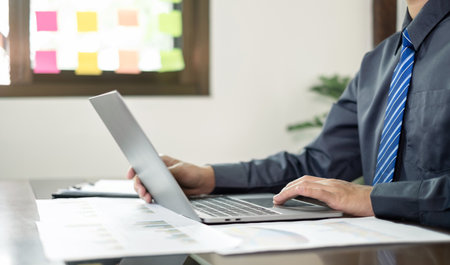The businessman hand sits at their desks and calculates financial graphs showing the results of their investments planning the process of successful business growth.の写真素材