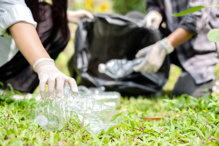 garbage collection, volunteer team pick up plastic bottles, put garbage in black garbage bags to clean up at parks, avoid pollution, be friendly to the environment and ecosystem.の写真素材