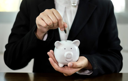 Hand putting coin into piggy bank. Saving money with coins Step into a business that is growing to be successful and save for retirement concepts.の写真素材