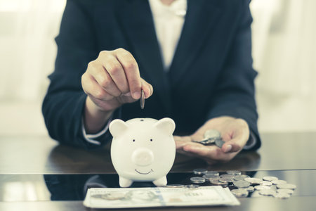 Hand putting coin into piggy bank. Saving money with coins Step into a business that is growing to be successful and save for retirement concepts.の写真素材