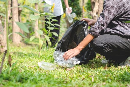 garbage collection, volunteer team pick up plastic bottles, put garbage in black garbage bags to clean up at parks, avoid pollution, be friendly to the environment and ecosystem.の写真素材