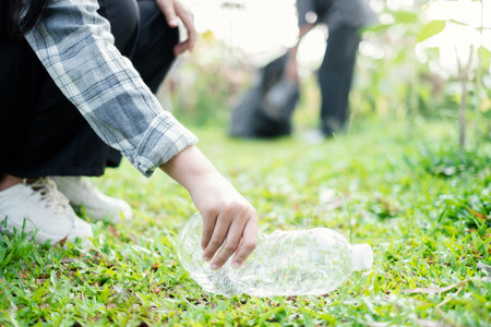 garbage collection, volunteer team pick up plastic bottles, put garbage in black garbage bags to clean up at parks, avoid pollution, be friendly to the environment and ecosystem.の写真素材