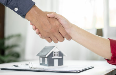 Businessmen and brokers real estate agents shake hand after completing negotiations to buy houses insurance and sign contracts. Home insurance concept.の写真素材