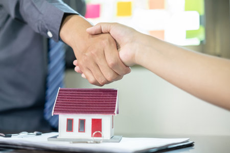 Businessmen and brokers real estate agents shake hand after completing negotiations to buy house insurance and sign contracts. Home insurance concept.の写真素材