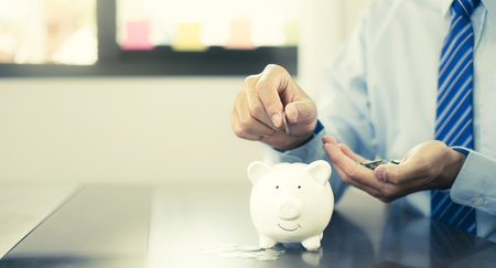 Hand putting coin into piggy bank. Saving money with coins Step into a business that is growing to be successful and save for retirement concepts.の写真素材