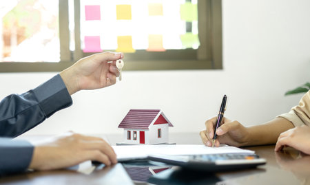 Real estate agent broker hand over the house key to the new owner after completing the signing according to agreement renting a house and buy house insurance Home insurance concept.の写真素材