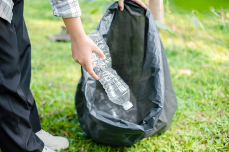 garbage collection, volunteer team pick up plastic bottles, put garbage in black garbage bags to clean up at parks, avoid pollution, be friendly to the environment and ecosystem.の写真素材