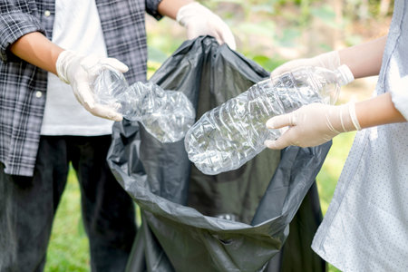 garbage collection, volunteer team pick up plastic bottles, put garbage in black garbage bags to clean up at parks, avoid pollution, be friendly to the environment and ecosystem.の写真素材