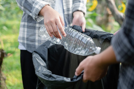 garbage collection, volunteer team pick up plastic bottles, put garbage in black garbage bags to clean up at parks, avoid pollution, be friendly to the environment and ecosystem.の写真素材