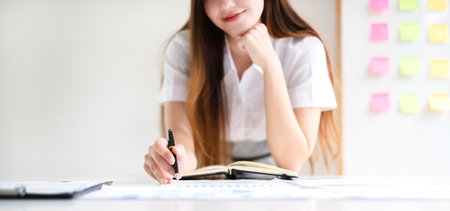 Asian businesswoman calculate financial graphs showing results about their investments and planning successful business growth process in the office.の写真素材
