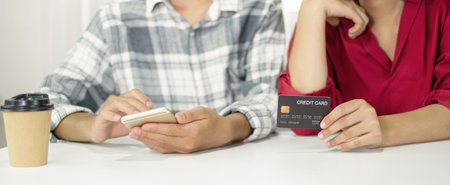 E-commerce Concept. Happy couple holding credit and using smartphone enter their card number in the...