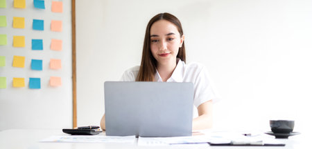 Asian businesswoman sit at their desks and calculate financial graphs showing results about their investments, planning successful business growth process.の写真素材