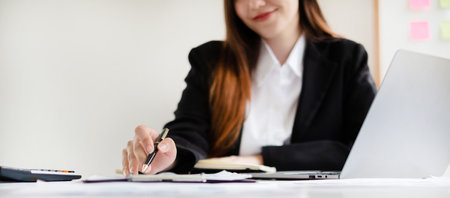 businesswomen sit at their desks and calculate financial graphs showing results about their...