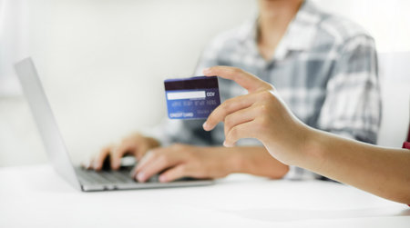 E-commerce Concept. Happy couple holding credit card enjoying doing online shopping and using laptop...