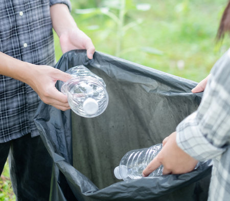garbage collection, volunteer team pick up plastic bottles, put garbage in black garbage bags to...
