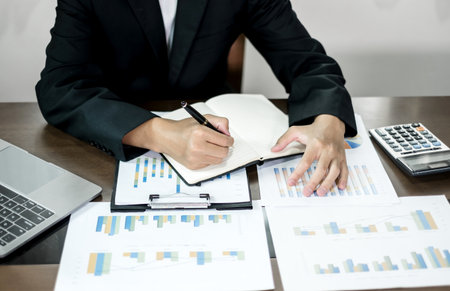The businessman hand sits at their desks and calculates financial graphs showing the results of...