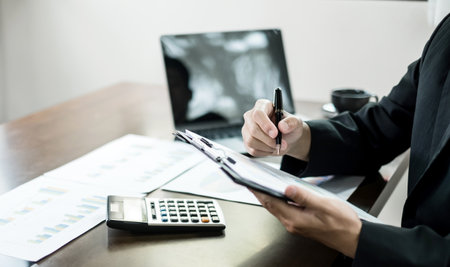 The businessman hand sits at their desks and calculates financial graphs showing the results of their investments planning the process of successful business growth.の写真素材