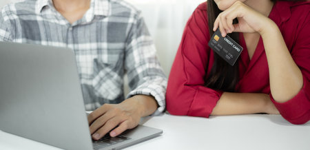 E-commerce Concept. Happy couple holding credit card enjoying doing online shopping and using laptop...
