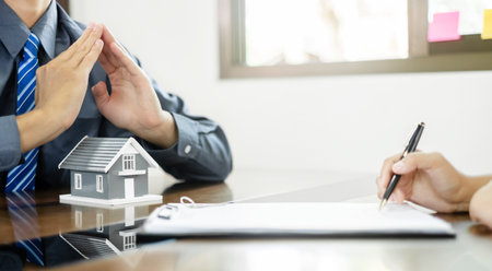 A real estate agent with a home model is talking to clients about renting a house buying home insurance and contracting the contract after the formal negotiation is completed.の写真素材