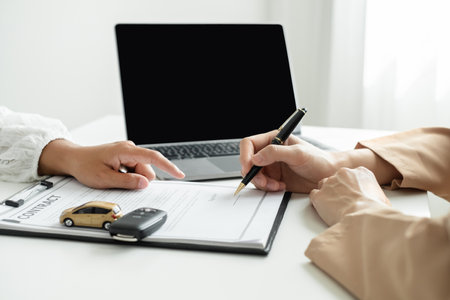 The car dealer provides advice on loans, insurance details, and car rental information, and delivers the car with the keys after the rental contract is signed.の写真素材