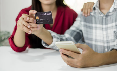 E-commerce Concept. Happy couple holding credit card enjoying doing online shopping and using laptop...