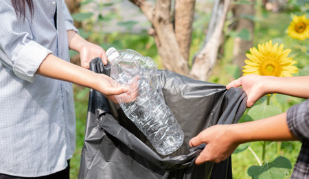garbage collection, volunteer team pick up plastic bottles, put garbage in black garbage bags to clean up at parks, avoid pollution, be friendly to the environment and ecosystem.の写真素材
