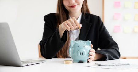 Asian woman putting coin into piggy bank. Saving money with coins Step into a business that is growing to be successful and save for retirement concepts.の写真素材