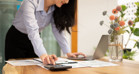 Asian businesswoman calculate financial graphs showing results about their investments and plan successful business growth process.の写真素材