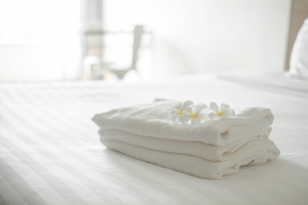 A hotel maid stacked towels on the bed and placed flowers on the towels in a hotel room.の写真素材