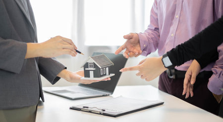 A real estate agent with a House model is talking to clients about buying home insurance. Home insurance concept.の写真素材