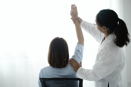 Female physiotherapists provide physical assistance to patients with shoulder injuries massaging their shoulders for muscle recovery in the rehabilitation center. Physiotherapy concepts.の写真素材