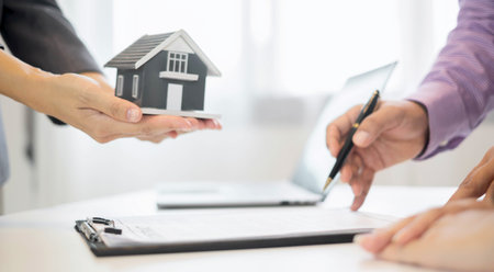 A real estate agent with a House model is talking to clients about buying home insurance. Home insurance concept.の写真素材