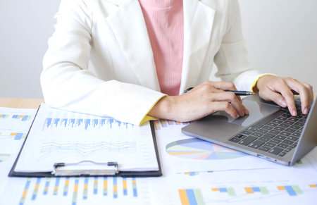 Asian businesswoman sit at their desks and calculate financial graphs showing results about their investments and plan successful business growth process.の写真素材