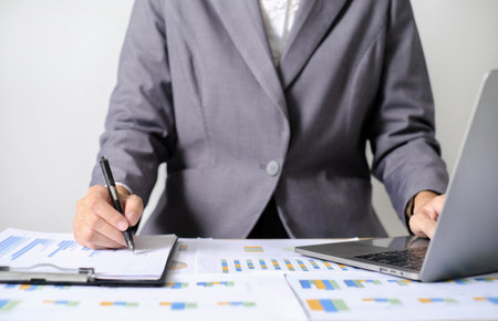 Asian businesswoman sit at their desks and calculate financial graphs showing results about their investments and plan successful business growth process.の写真素材
