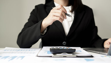 Asian businesswoman sit at their desks and calculate financial graphs showing results about their investments and plan successful business growth process.の写真素材