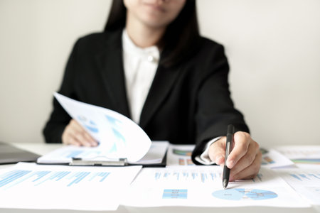Asian businesswoman sit at their desks and calculate financial graphs showing results about their investments and plan successful business growth process.の写真素材