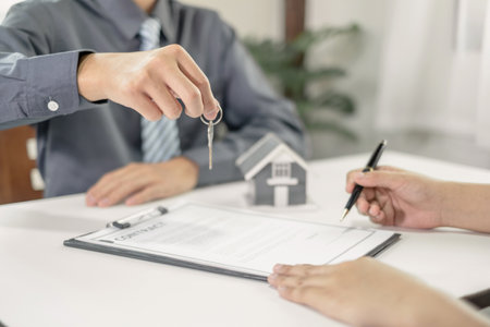 Real estate agent broker hand over the house key to the new owner after completing the signing according to the agreement renting a house and buy house insurance Home insurance concept.の写真素材