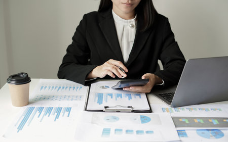 Asian businesswoman sit at their desks and calculate financial graphs showing results about their investments and plan successful business growth process.の写真素材