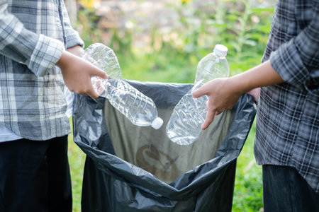 garbage collection, volunteer team pick up plastic bottles, put garbage in black garbage bags to clean up at parks, avoid pollution, be friendly to the environment and ecosystem.の写真素材