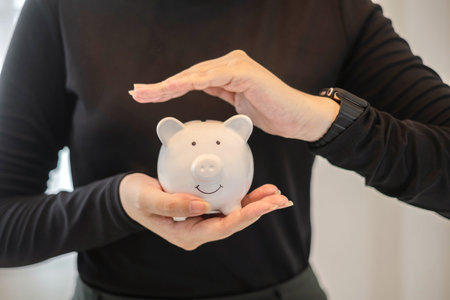 A young woman teaches how to put coins in a piggy bank start a growing business for success and save for retirement concept.の写真素材