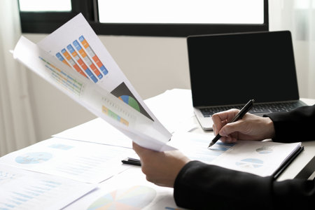 Asian businesswoman sit at their desks and calculate financial graphs showing results about their investments and plan successful business growth process.の写真素材