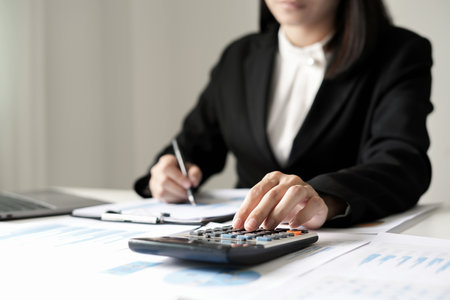 Asian businesswoman sit at their desks and calculate financial graphs showing results about their investments and plan successful business growth process.の写真素材