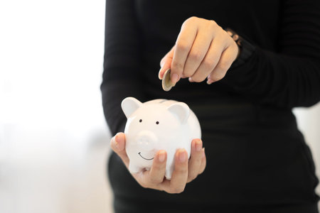 A young woman teaches how to put coins in a piggy bank start a growing business for success and save for retirement concept.の写真素材