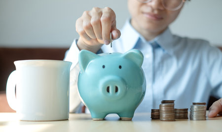 A young woman teaches how to put coins in a piggy bank start a growing business for success and save for retirement concept.の写真素材