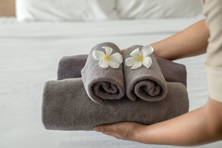 A hotel maid stacked towels on the bed and placed flowers on the towels in a hotel room.の写真素材